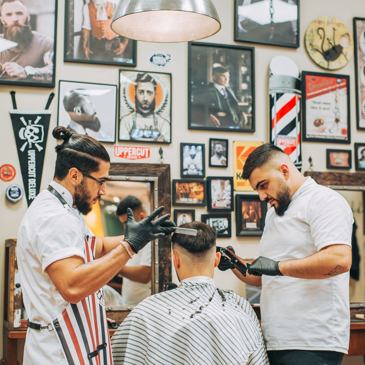 Två barberare arbetar med en kund hos Peter’s Barbershop i Älvsjö